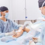 Medical professionals performing a procedure on a patient's leg in a clinic